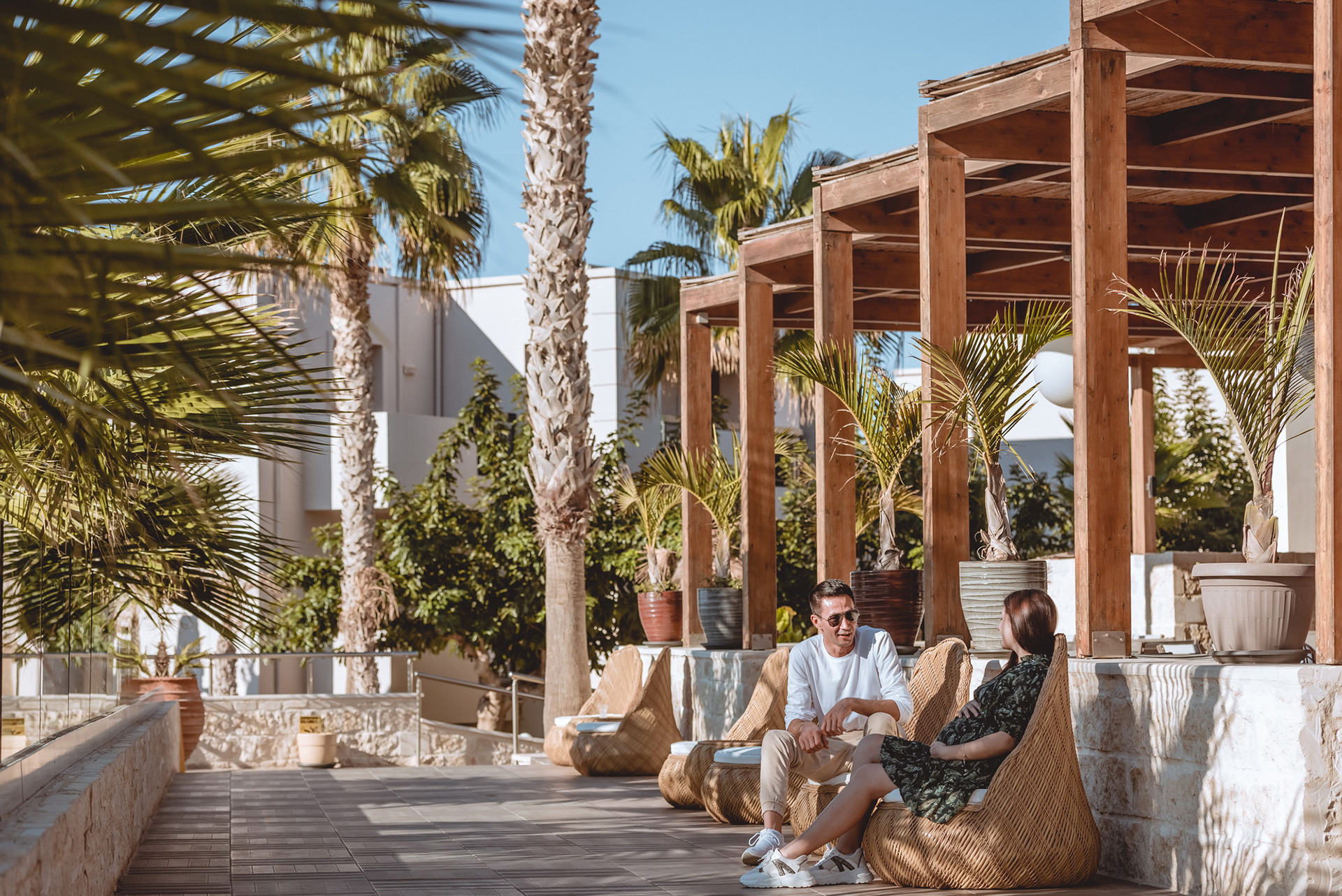 Couple relaxing on the shaded terrace with wooden pergola at Gouves Water Park Holiday Resort in Crete