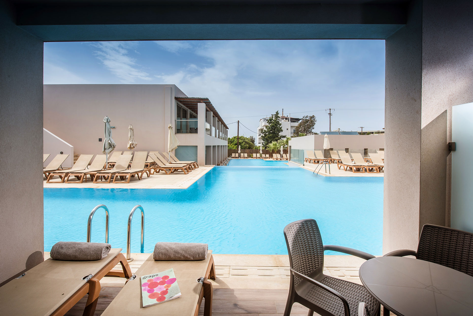 Gouves Park Family Suite Swim Up balcony view with a table, chairs and two sunbeds in front of the pool