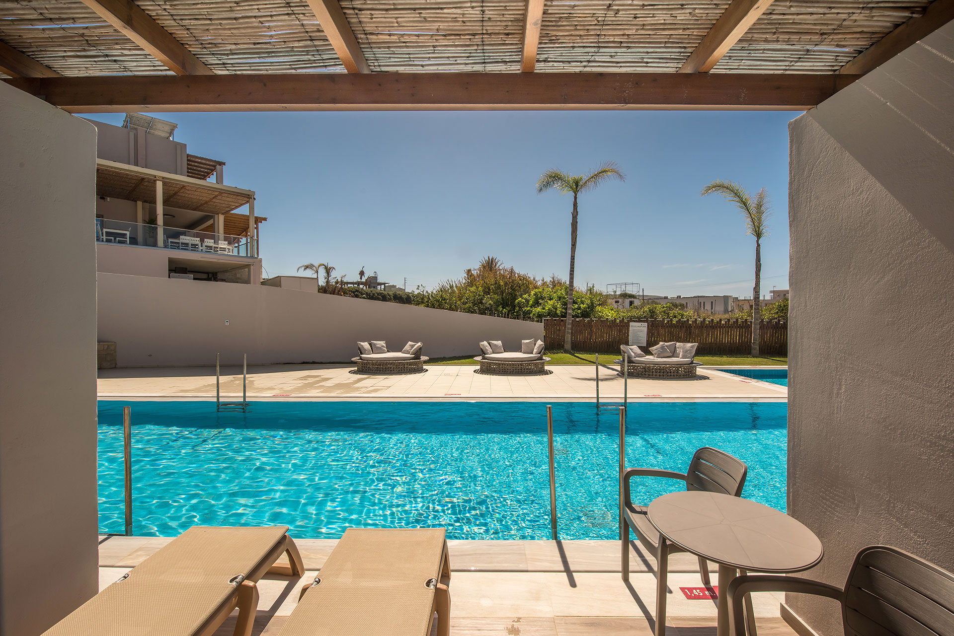 Gouves Park Maisonette Swim Up terrace with two sunbeds, a table with two chairs and access to the pool