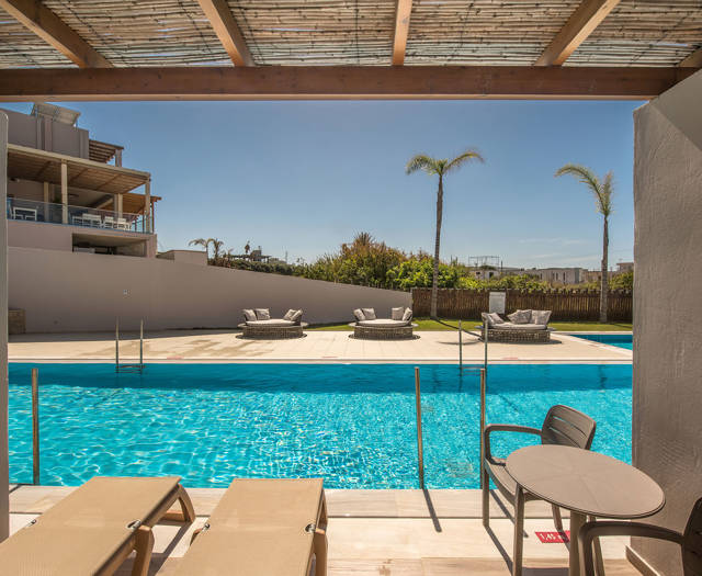 Gouves Park Maisonette Swim Up terrace with two sunbeds, a table with two chairs and access to the pool