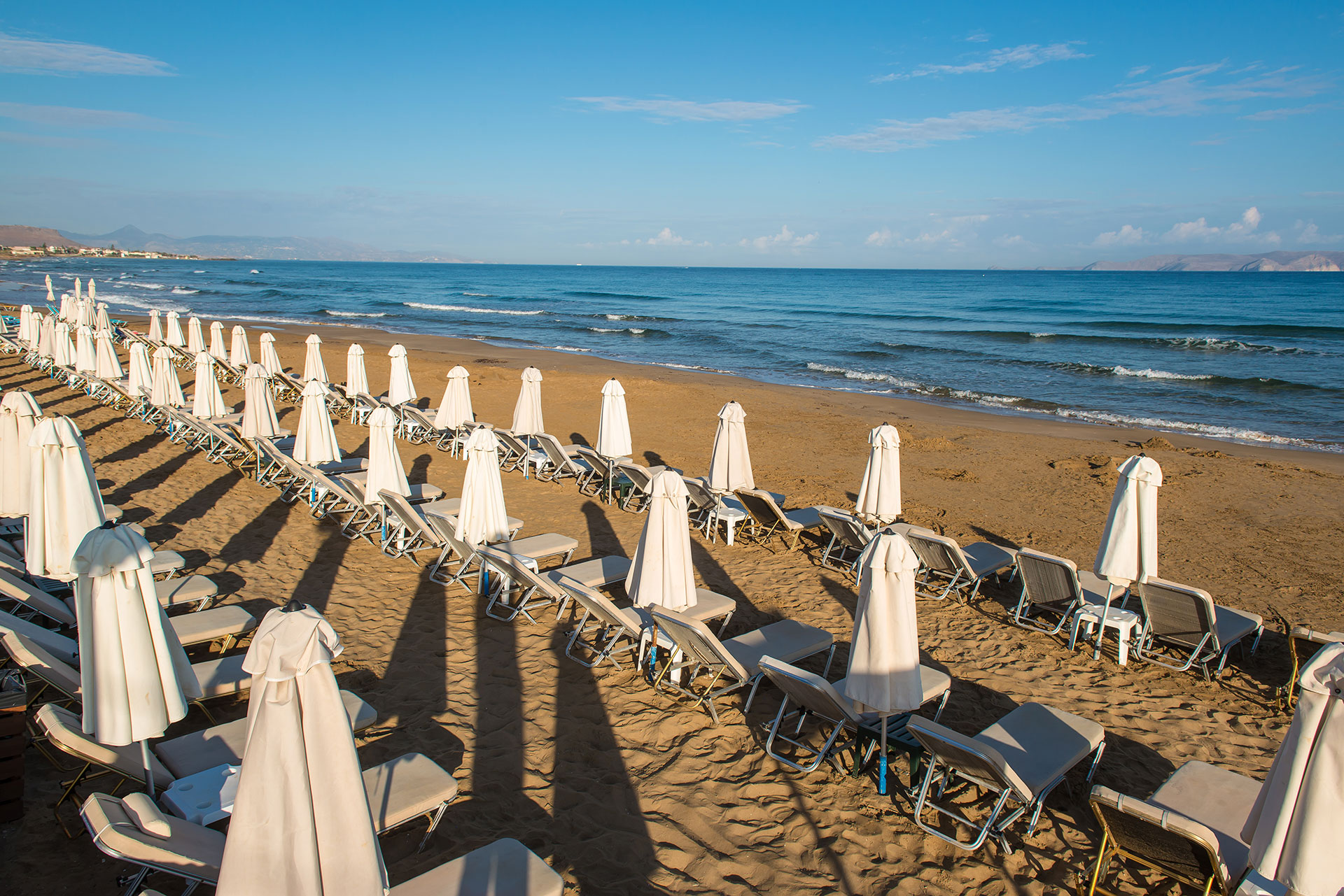 Sandy beach with sunbeds and umbrellas in front of the sea