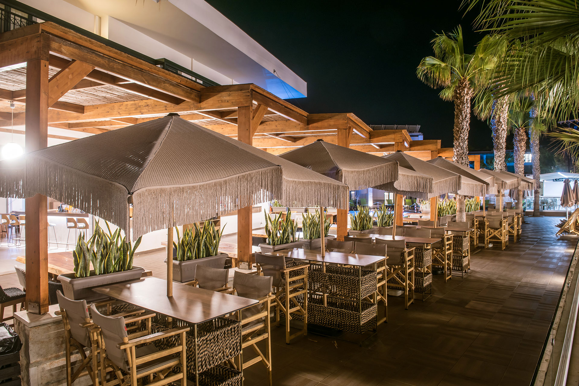 Gouves Park Apollon Bar outdoor sitting area with tables for four, chairs and umbrellas