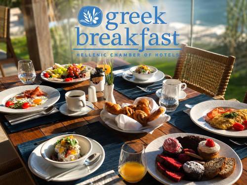 Table filled with greek breakfast plates, featuring omelets, coffee, fresh juice, eggs, cakes and sweets