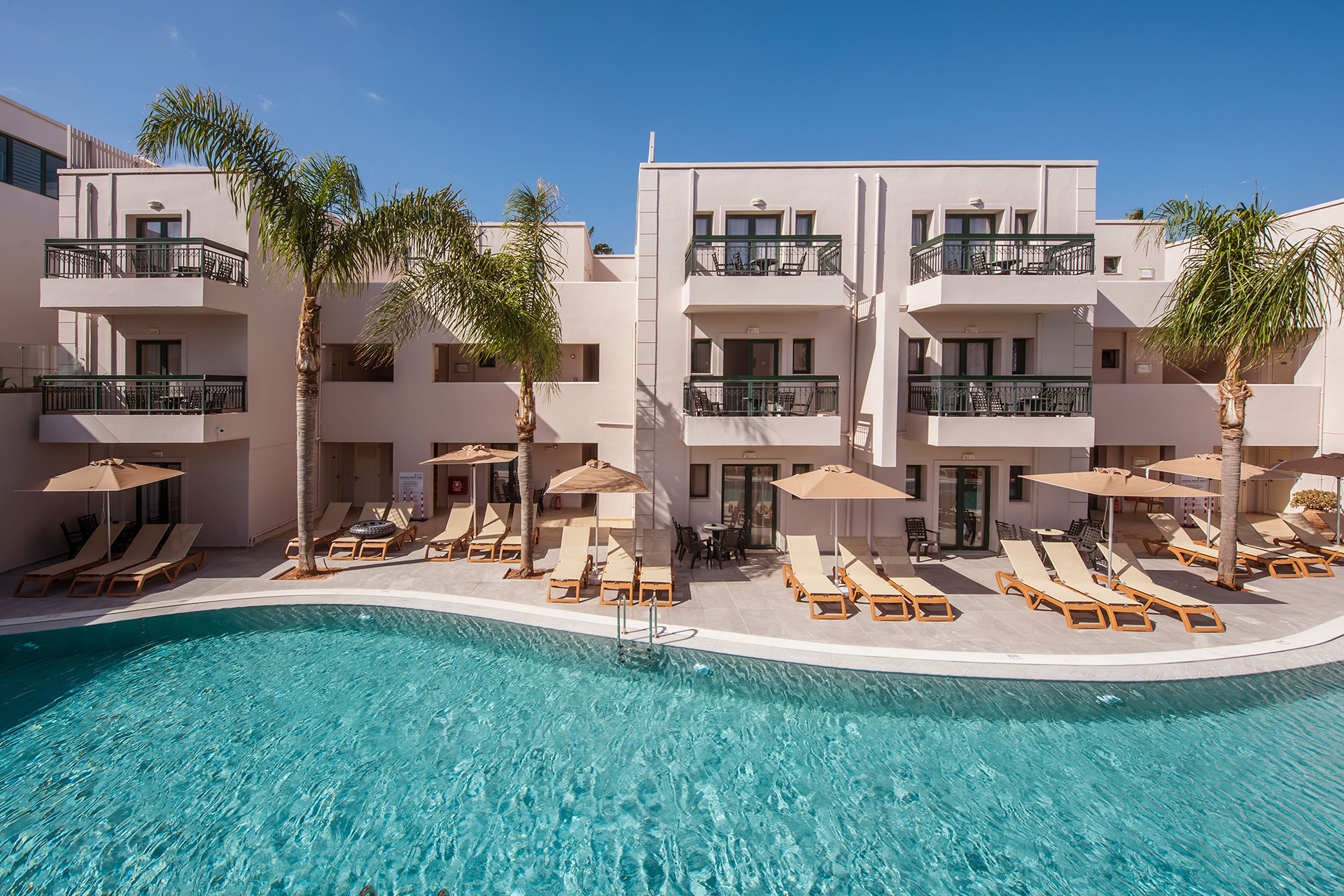 Gouves Park view of the pool with sunbeds, umbrellas and the straight view of the hotel in the background