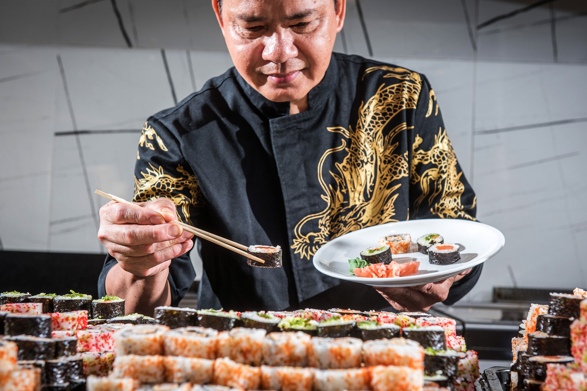 Gouves Park Umami Asian Restaurant chef holding a plate in front of the sushi buffet