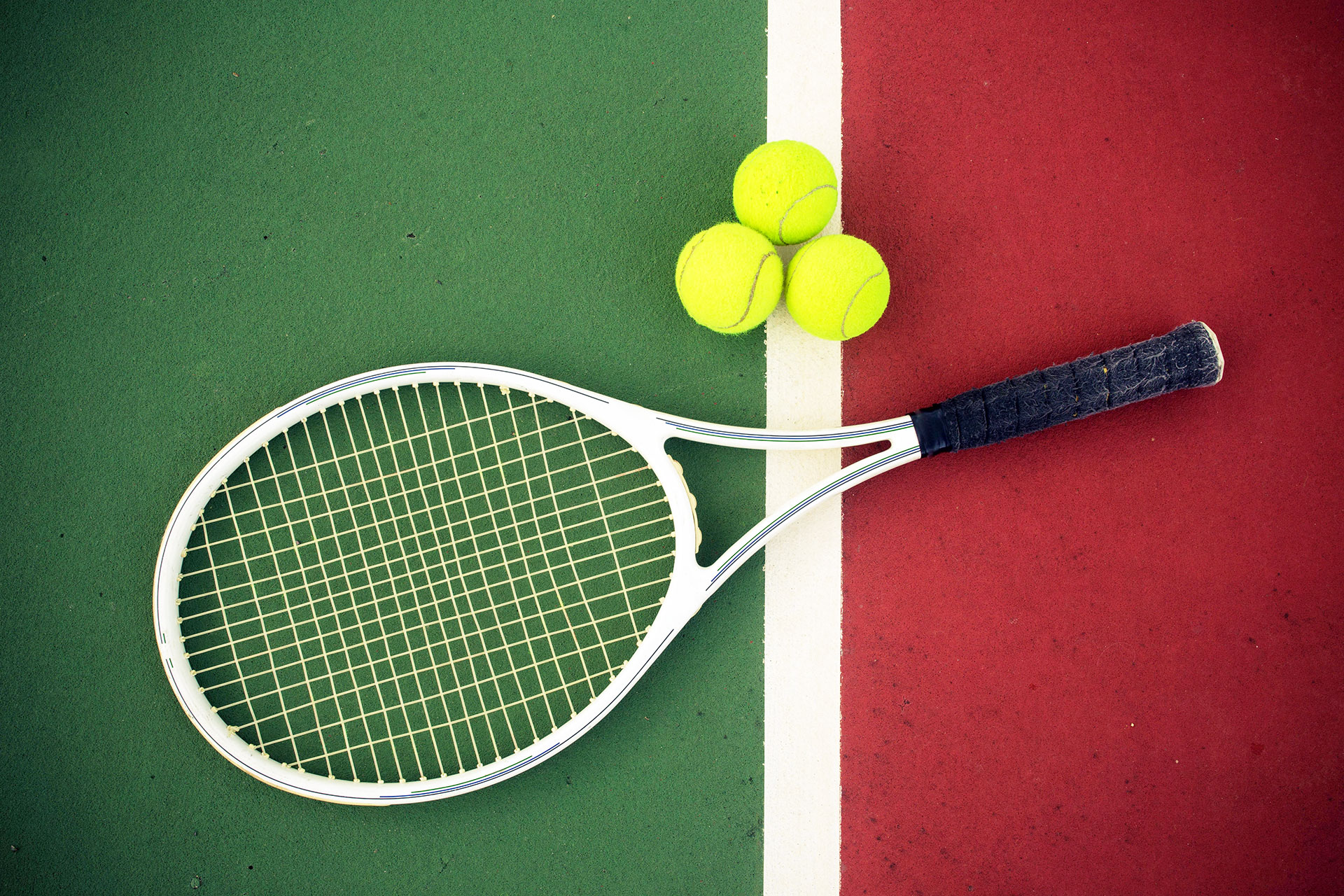 Gouves Park tennis racket and 3 tennis balls laying in the middle of a tennis court